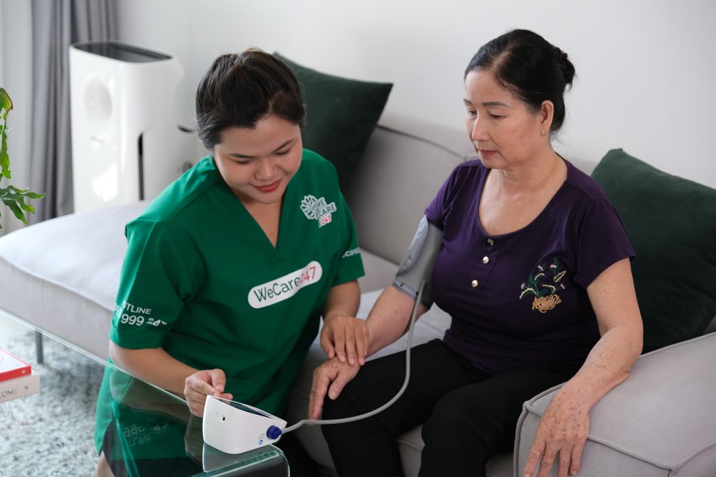 Chăm sóc viên WeCare 247 đang đo huyết áp và chăm sóc sức khoẻ người cao tuổi.